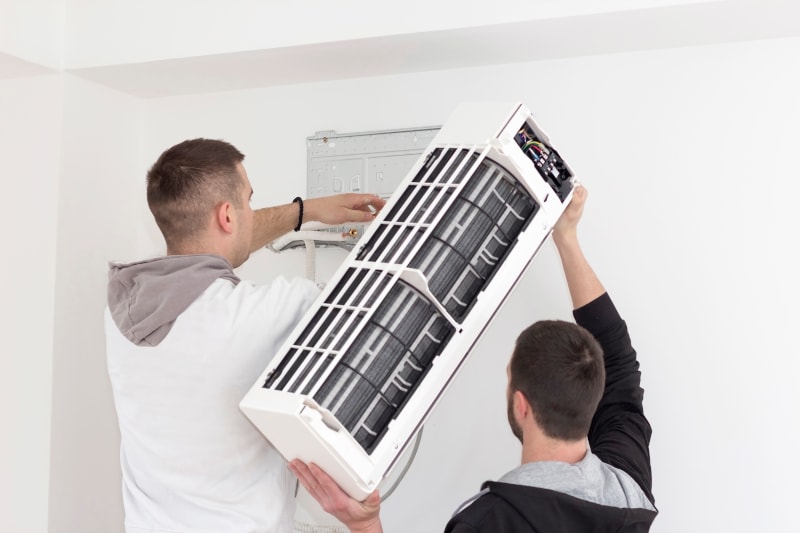 Two HVAC Technicians installing HVAC unit
