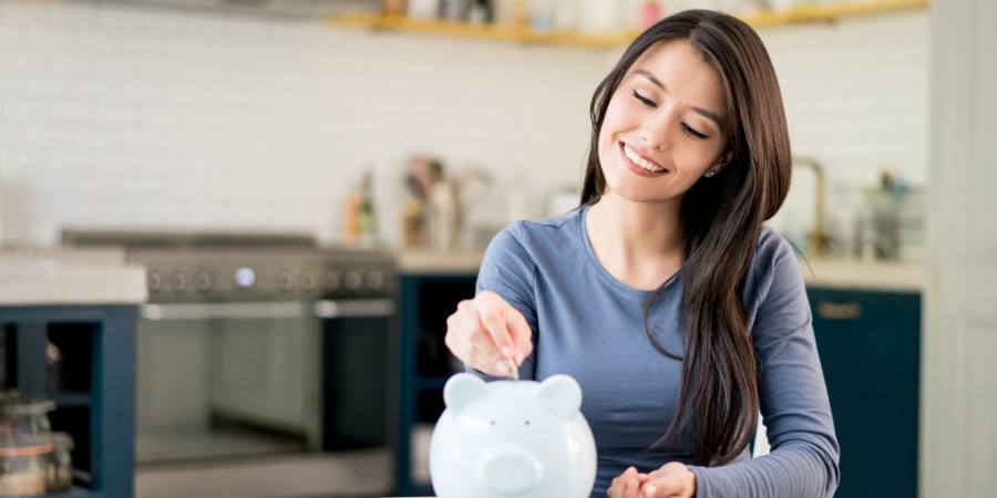 woman putting coins into a piggy bank